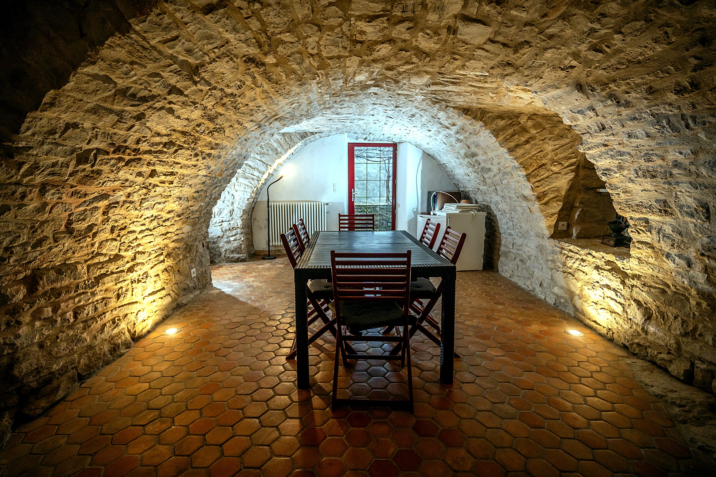 Salle commune voûtée en pierre avec bar, gîte L'Oustal du Larzac